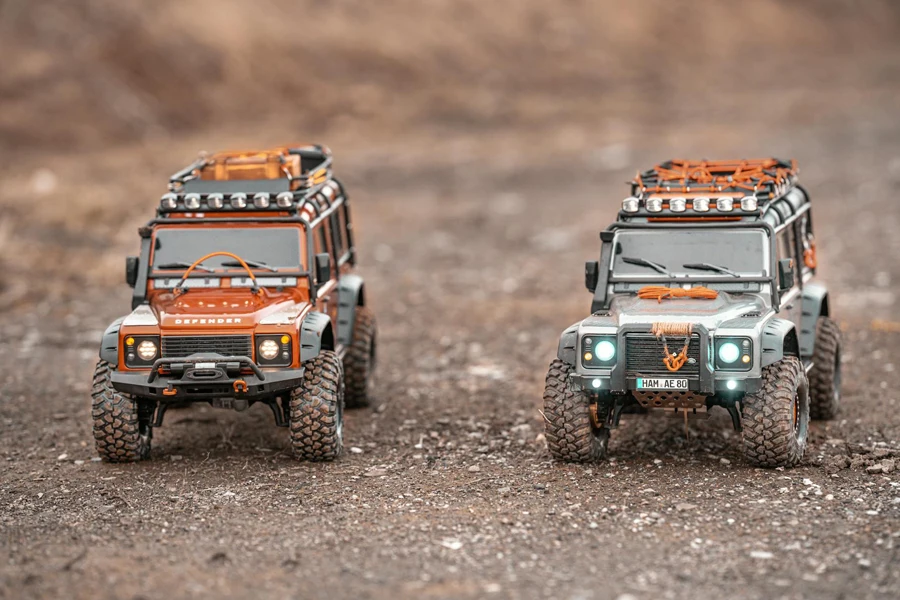 Small toy figures of off road cars with shining headlights placed on ground