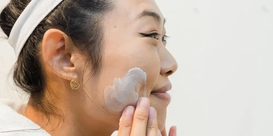 Smiling Woman Applying Facial Cream on Her Face