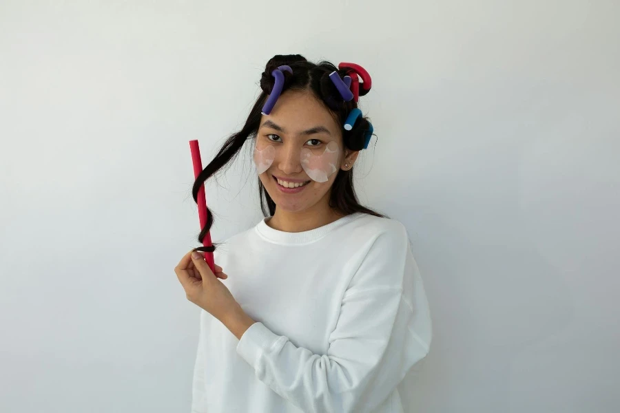Smiling ethnic woman with eye patches and curlers on head