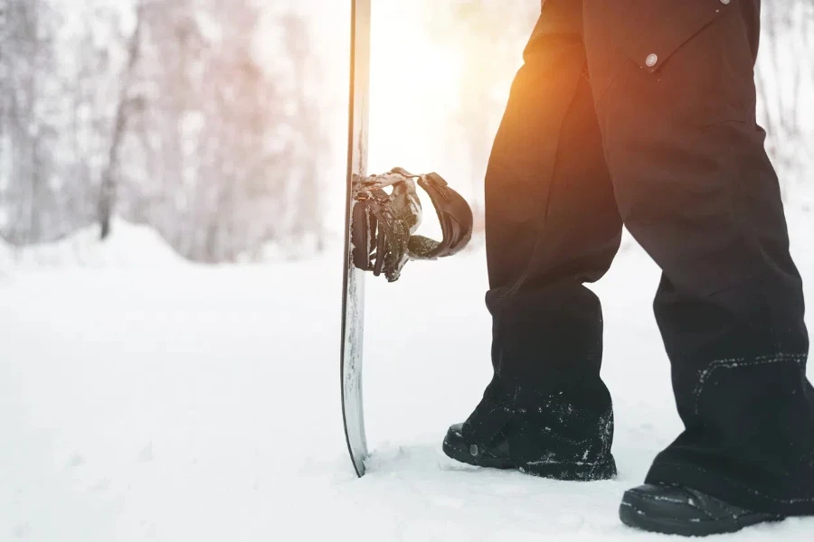 Snowboarder standing with snowboard over winter snow background