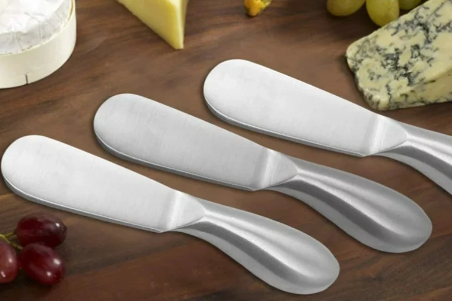 Three cheese spreaders on a cheeseboard