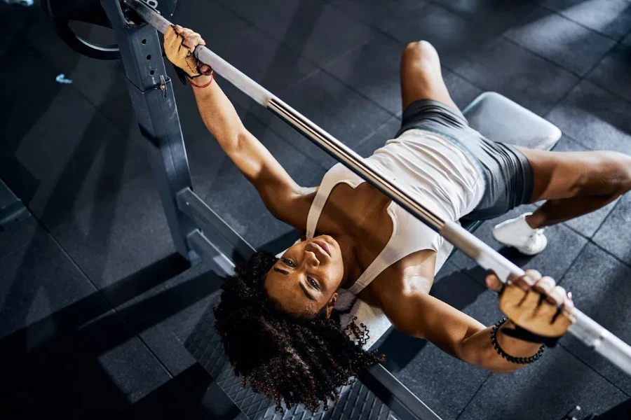 Top view of a lovely tranquil female weightlifter doing the bench press at the gym