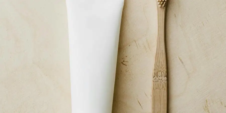 Top view of white mockup toothpaste tube and bamboo toothbrush placed on light brown wooden surface by Karolina Kaboompics
