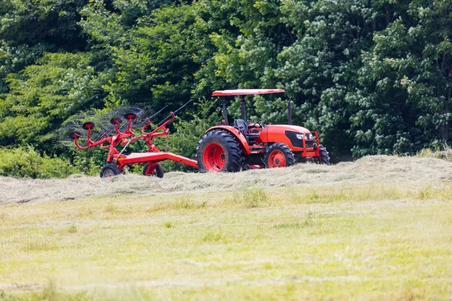 Tractor pulling a wheel rake for making round bales of hay