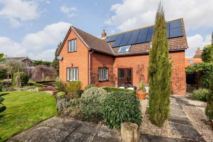 Traditional detached brick home within landscaped gardens with array of roof mounted photovoltaic solar panels