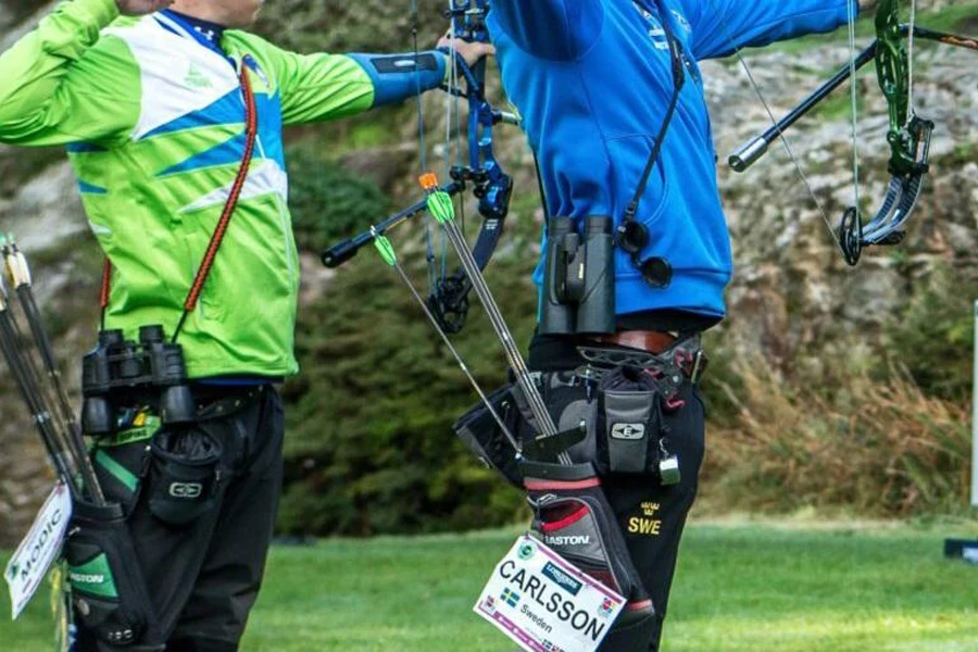 Two archers shooting on a field with hip quivers