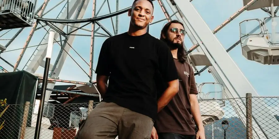 Two people standing in front of a ferris wheel by Camilo Ospina