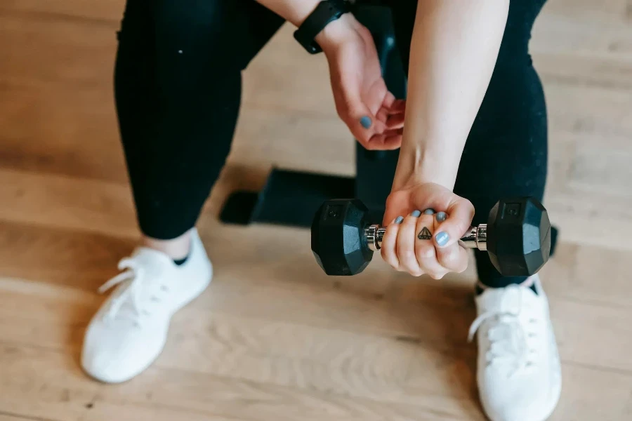 Unrecognizable woman training with dumbbell in sport club 