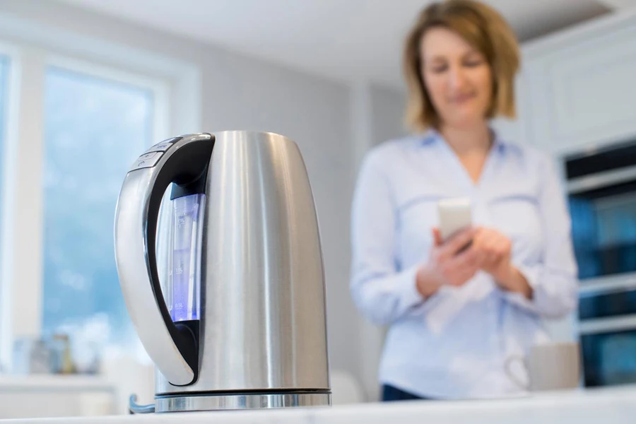 Woman Controlling Smart Kettle Using App On Mobile Phone
