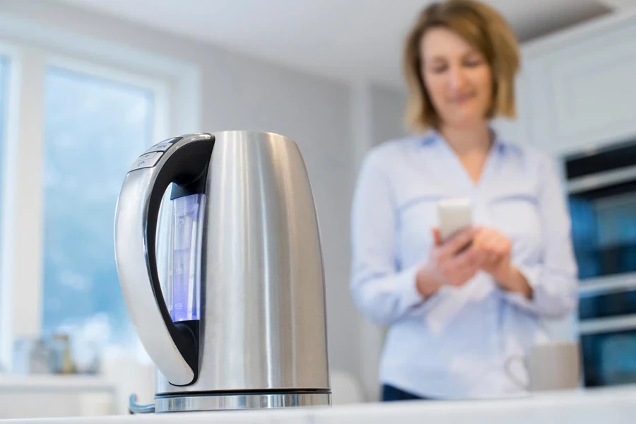 Woman Controlling Smart Kettle Using App On Mobile Phone