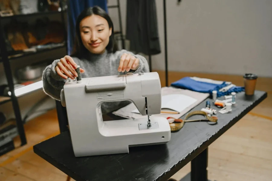 Woman Sitting at Table Sewing at Machine 