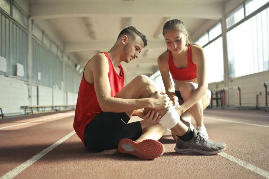 Woman Wrapping Man's Leg with Bandage 