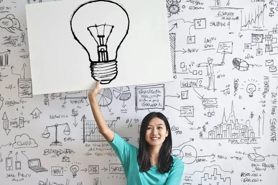 Woman draw a light bulb in a white board