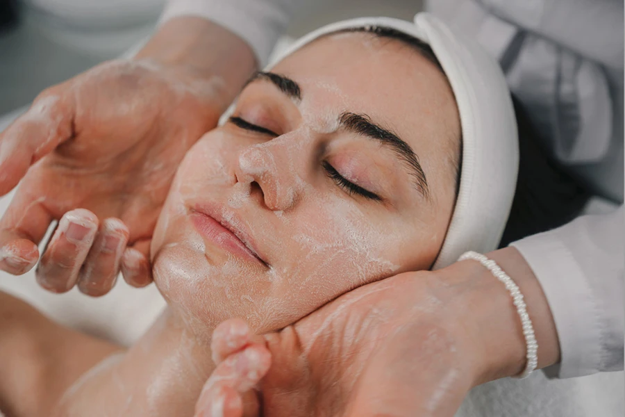 Woman getting facial foam massage at spa salon