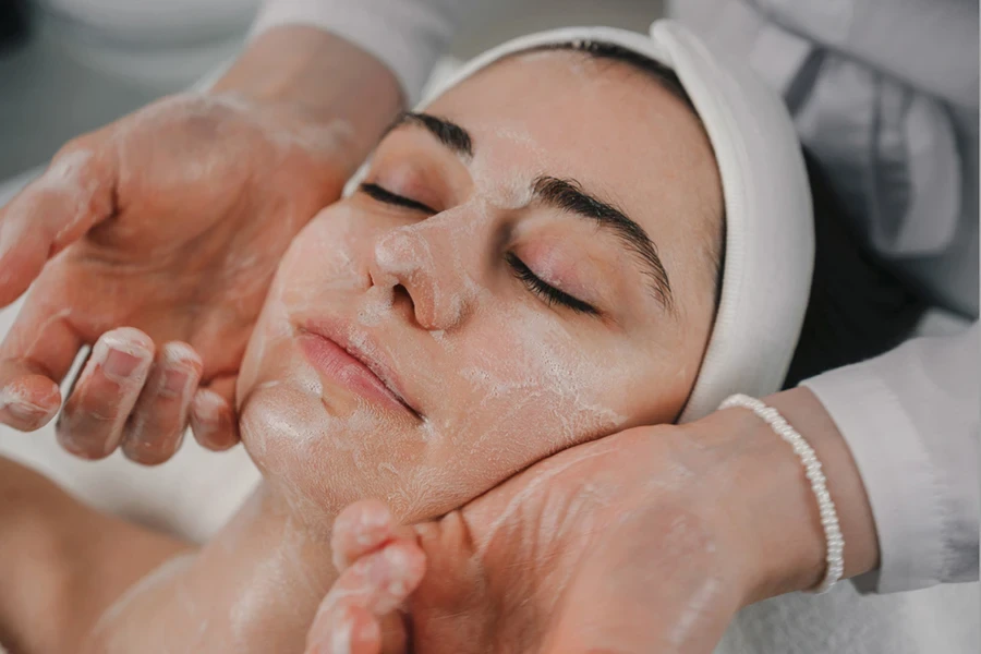 Woman getting facial foam massage at spa salon