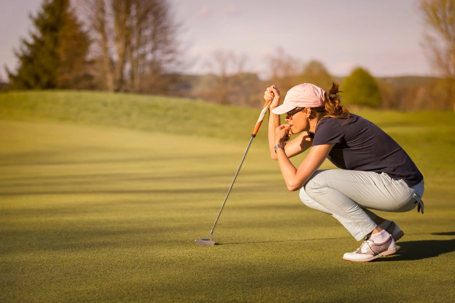 Woman golf player crouching and study the green before putting shot 