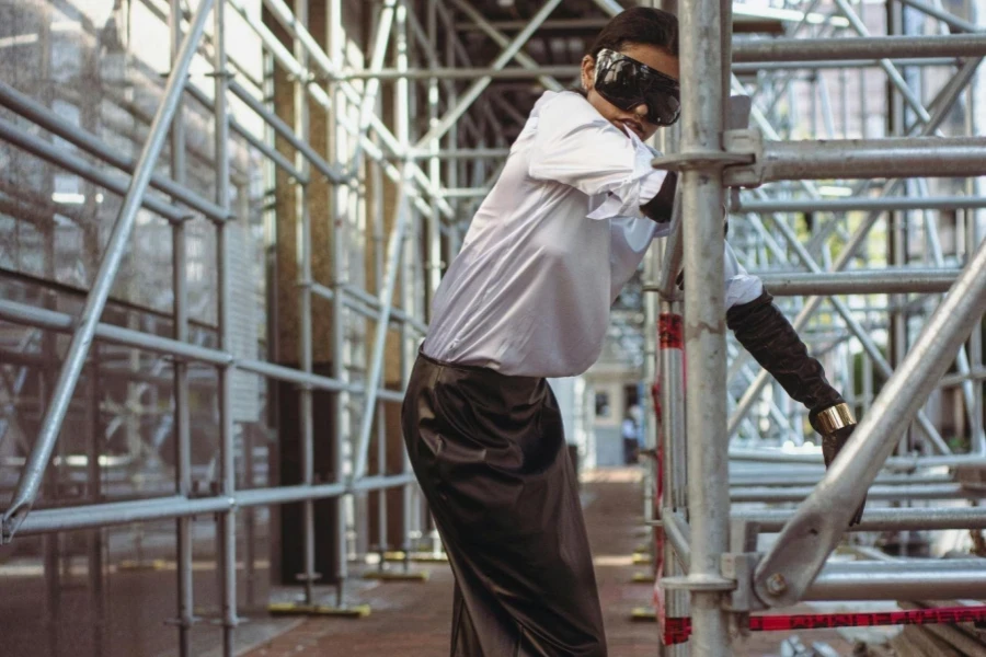 Woman in Goggles and Skirt Standing by Scaffolding