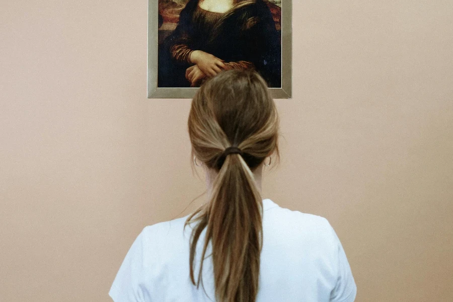 Woman in White Shirt Looking At A Painting Of Mona Lisa With Face Mask