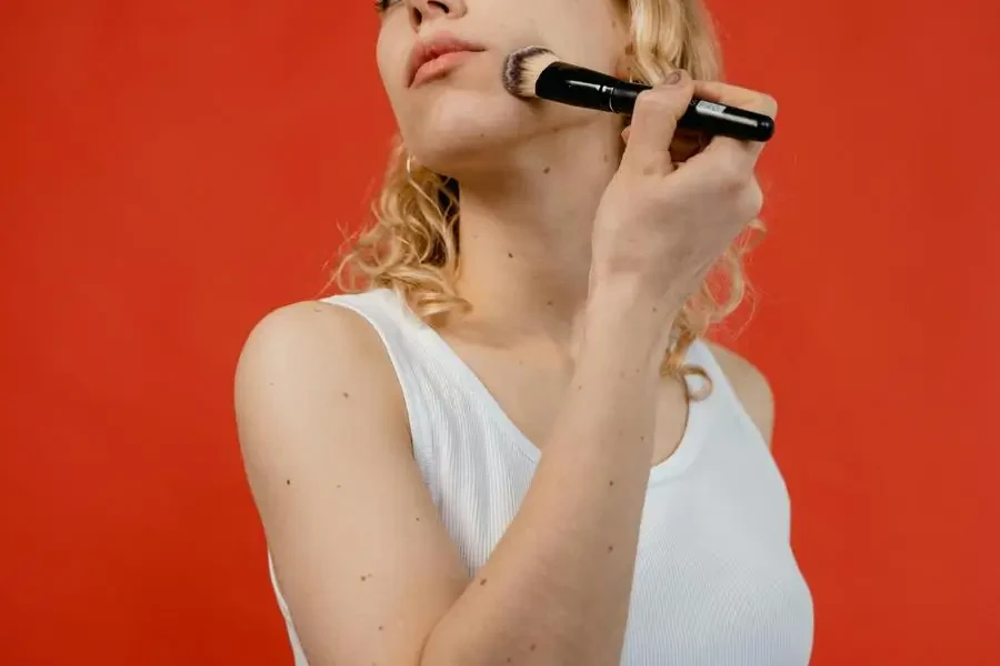 Woman in White Tank Top Applying Concealer by MART PRODUCTION