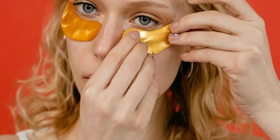 Woman in White Tank Top Putting Under Eye Masks by MART PRODUCTION