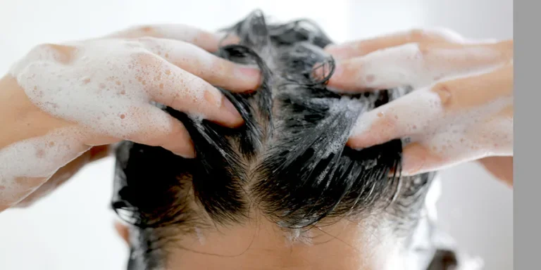Woman is washing her hair with shampoo