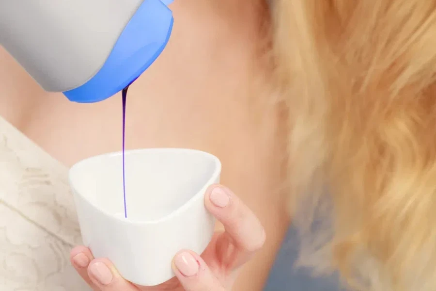 Woman pouring purple shampoo toner into white bowl 