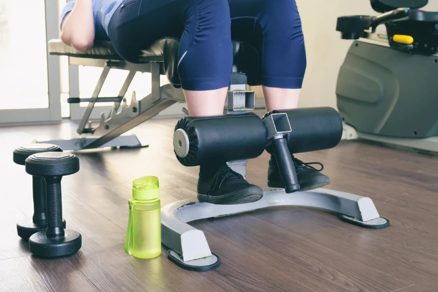 Woman works out in the gym, trains the muscles of the press. Women's legs on the simulator during a workout