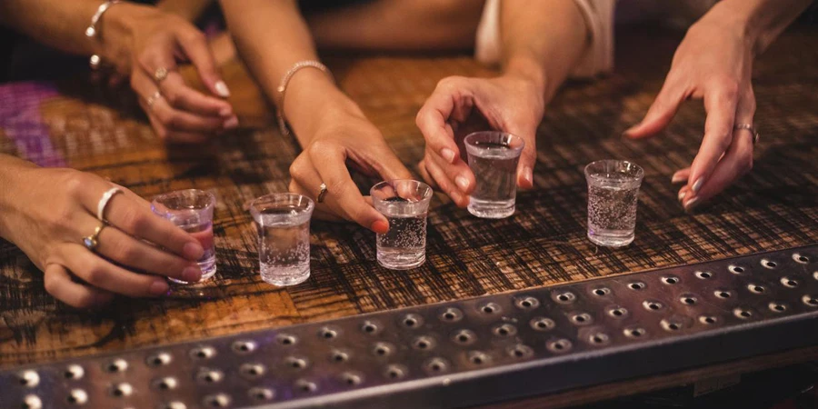 Women about to pick up some shot glasses for their night out.
