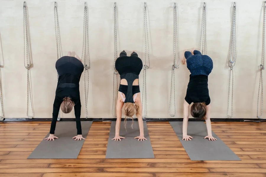 Women learning to stand on hands near wall. Upside down yoga position