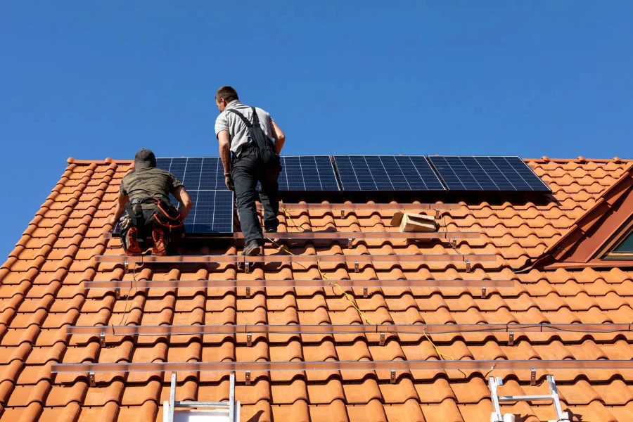 Workers installing solar electric panels on a house roof in Ochojno