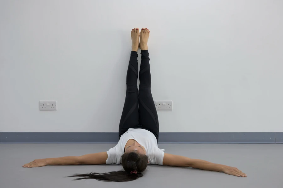 Yoga woman feet up relaxing on wall background