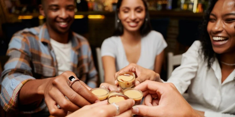 Young multiracial group of friends doing celebratory toast with drinks at restaurant