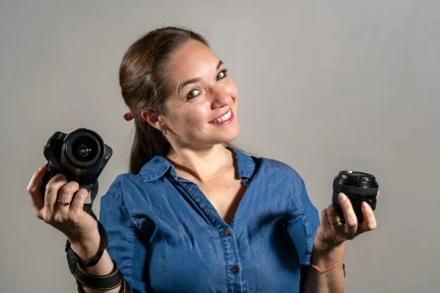 Young woman comparing a professional camera with a new lens