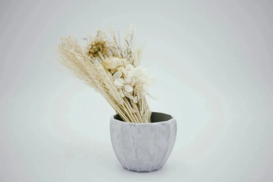 A gray bowl vase with artificial plant