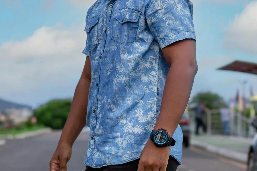 A man wearing a blue short sleeve shirt and black pants