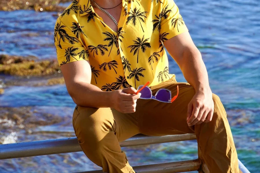 A man wearing a floral printed shirt and brown pants