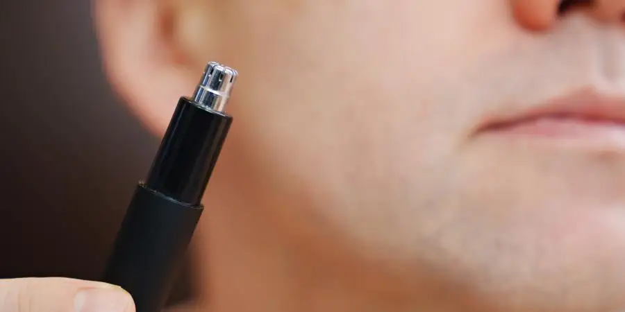 a man with trimmers for cutting hair in nose and ears