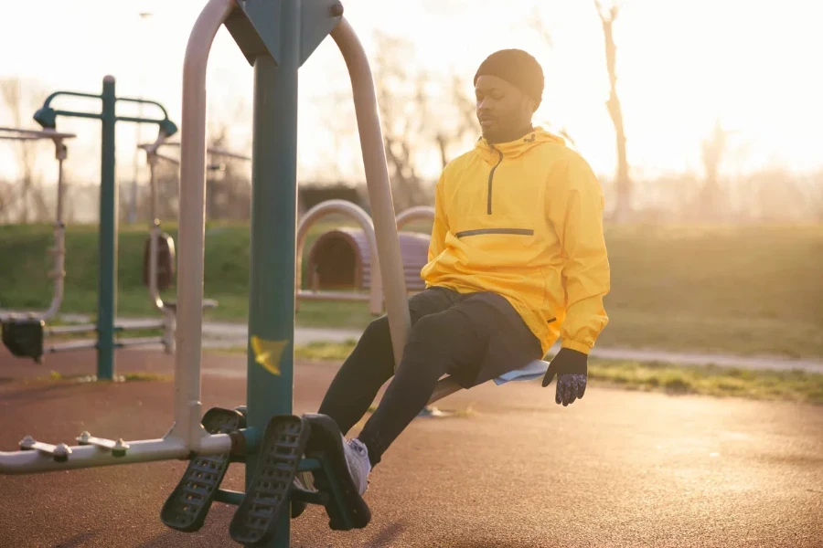 a man working out, doing exercises on leg press machine in sunrise