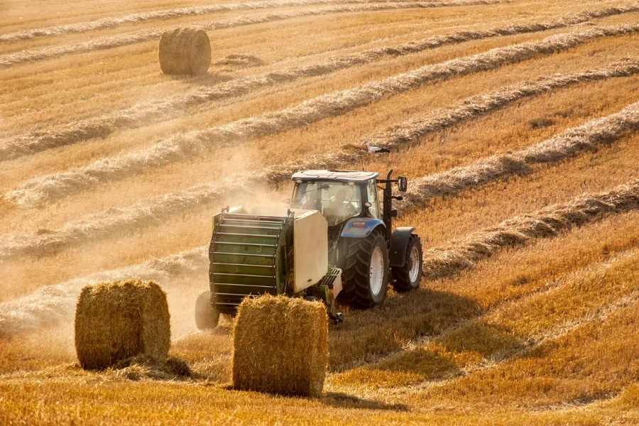 a tractor forms bales on the hills of straw field ,