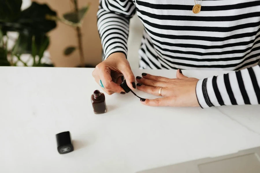 female doing manicure with black nail polish on