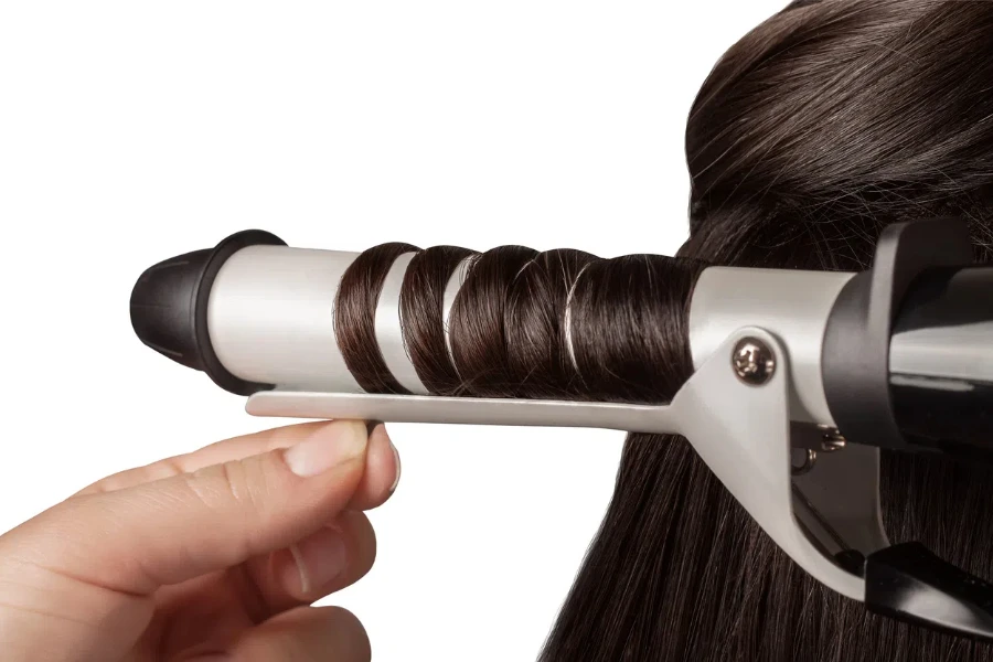 hair curling process. Hairdresser woman curls her hair