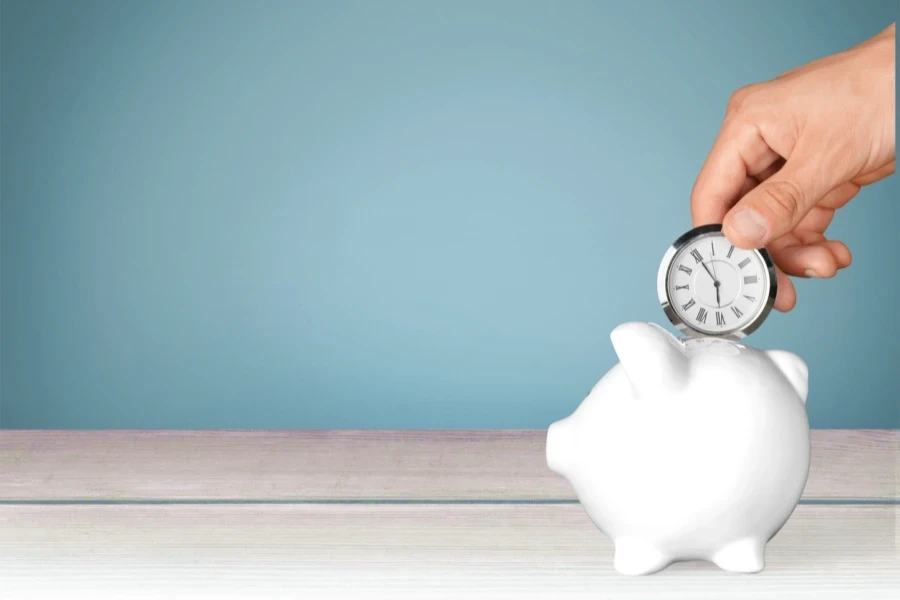 hand depositing clock in piggy bank