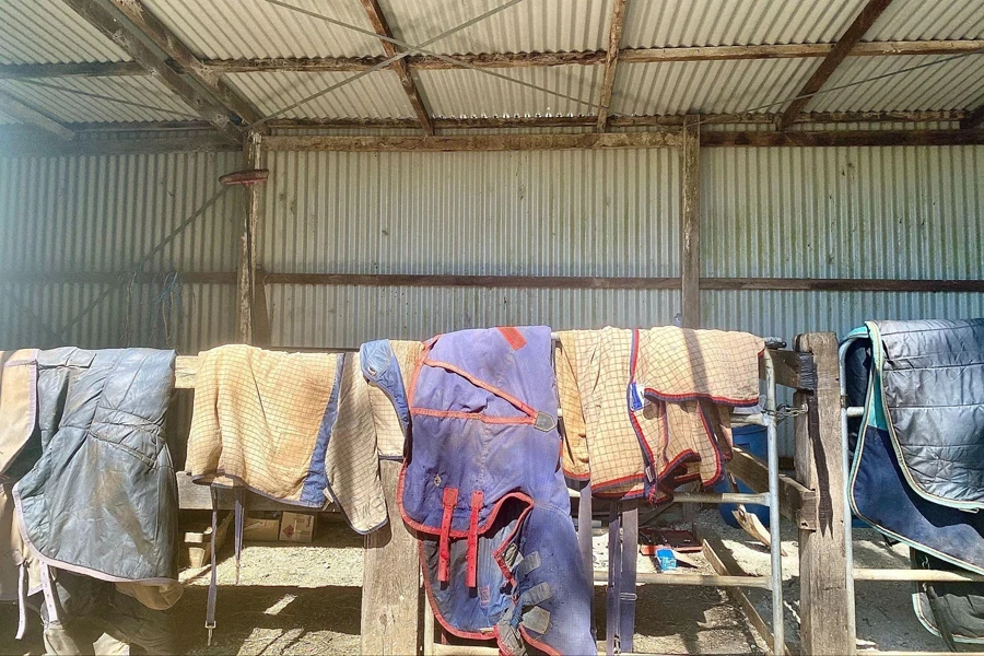 horse rugs hanging on wood stable