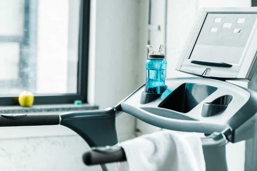 selective focus of bottle with drink near treadmill in gym