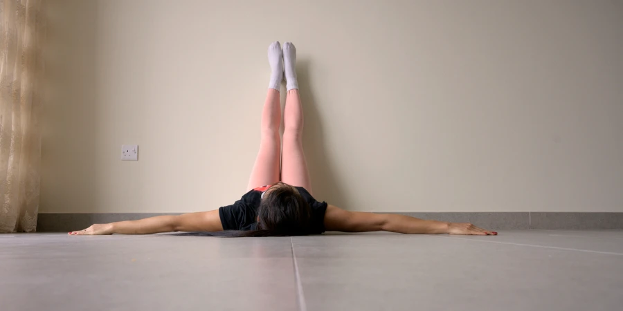 Woman laying on floor relaxing feet up on wall background