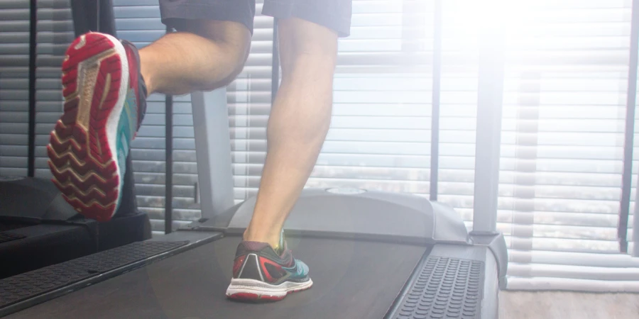 legs of a running man on a treadmill in a sunny morning