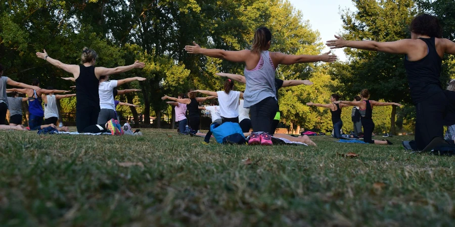 Women Performing Yoga on Green Grass Near Trees