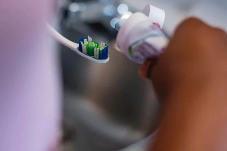 Photo of a Person Applying Toothpaste on a Toothbrush