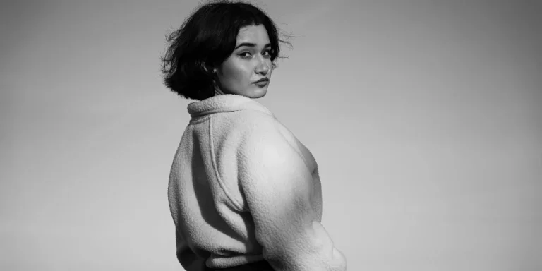 A woman in a white sweater standing on the beach