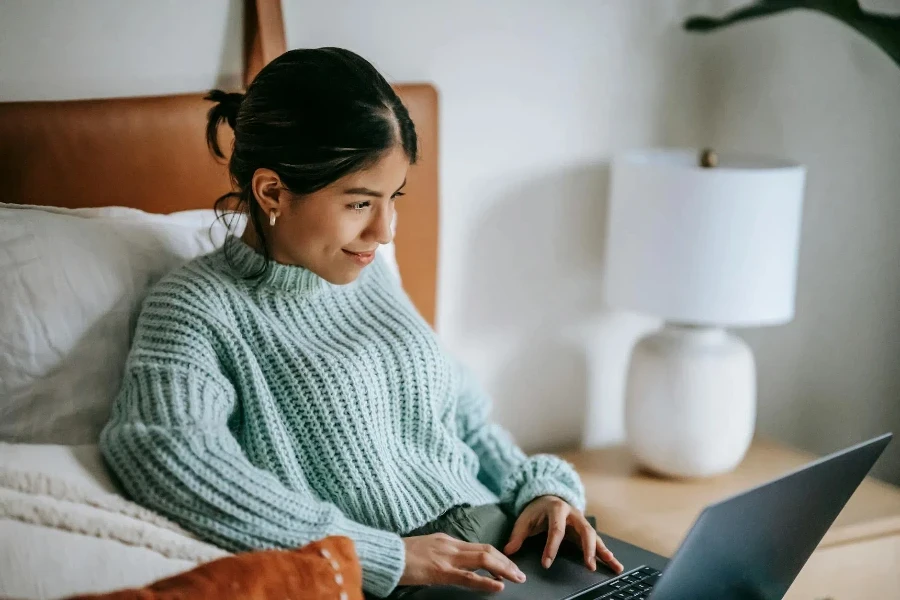 Happy ethnic woman surfing internet on laptop while using touchpad